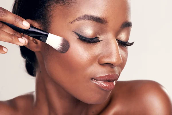 Cepilla más de tu belleza. Estudio de una hermosa joven aplicando rubor con un cepillo de maquillaje. —  Fotos de Stock