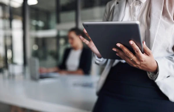 Het apparaat dat meer doet. Gehakte foto van een onherkenbare zakenvrouw met behulp van een digitale tablet in een kantoor met haar collega op de achtergrond. — Stockfoto