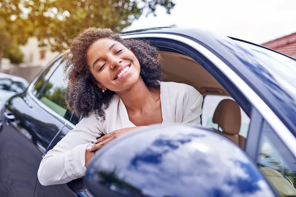Feeling the wind in her hair. Shot of an attractive young businesswoman leaning out of her window while driving to work on her morning commute. — Stock Photo, Image