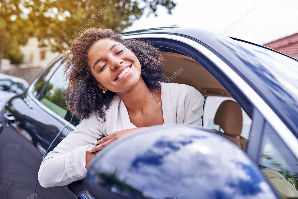 Feeling the wind in her hair. Shot of an attractive young businesswoman leaning out of her window while driving to work on her morning commute.