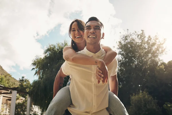 Denne kjærligheten får fram mitt indre barn. Skutt av en kjekk, ung mann som gir kjæresten sin en tur på ryggen mens han knytter bånd ute om dagen. – stockfoto