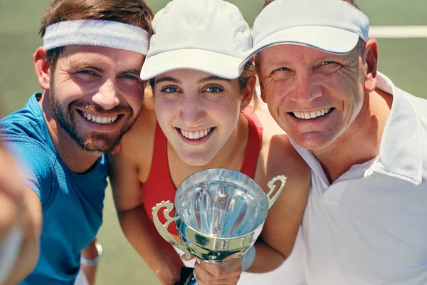 Großes Lächeln nach dem Sieg. Ausgeschnittenes Porträt einer Gruppe von Sportlern, die zusammenstehen und eine Trophäe in der Hand halten, nachdem sie ein Tennisspiel gewonnen haben. — Stockfoto