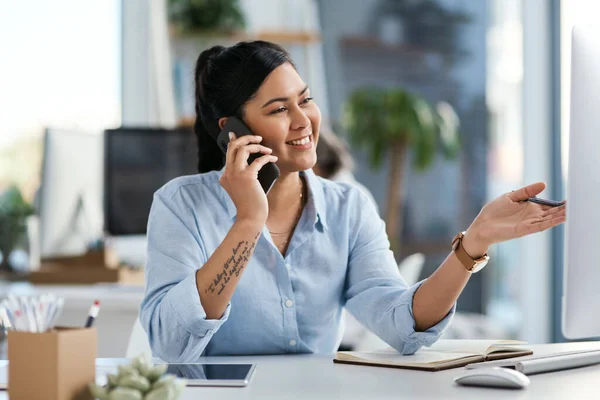 Het is jouw passie die je naar succes zal leiden. Shot van een jonge zakenvrouw praten op een mobiele telefoon tijdens het werken op een computer in een kantoor. — Stockfoto