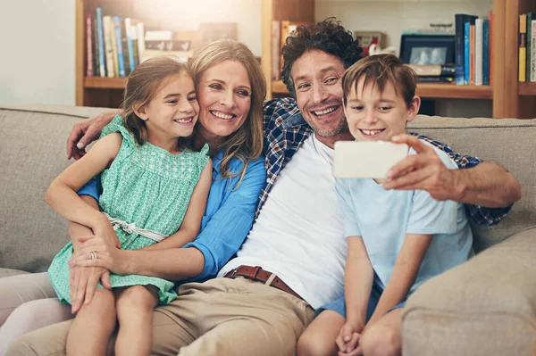 Szczęśliwa, żwawa rodzina. Zdjęcie szczęśliwej rodziny robiącej sobie selfie na komórce w domu. — Zdjęcie stockowe