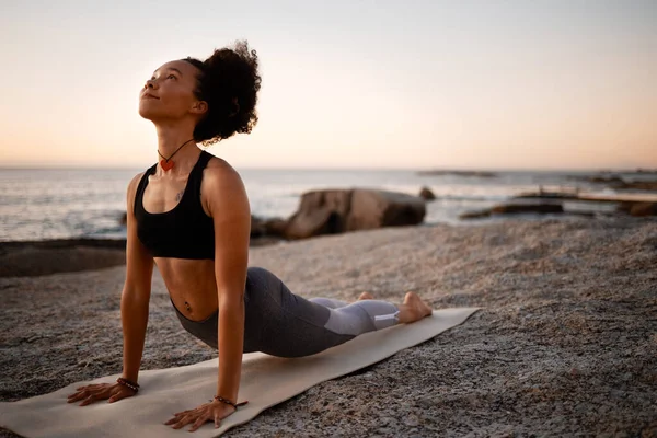 Небо має всі відповіді. Повнометражний знімок привабливої молодої жінки, що практикує йогу на пляжі під час заходу сонця . — стокове фото