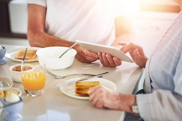 아침먹고 돌아다니고 있어. 집에서 아침 식사를 하면서 디지털 태블릿을 사용하는 노인 부부의 사진을 클로즈업. — 스톡 사진