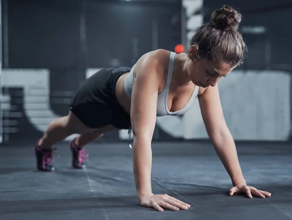 És tão forte quanto te esforças para ser. Tiro de uma jovem mulher fazendo flexões em um ginásio. — Fotografia de Stock