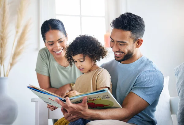 Της μαθαίνω νέα πράγματα. Φωτογραφία μιας νεαρής οικογένειας που διαβάζει ένα βιβλίο μαζί στο σπίτι. — Φωτογραφία Αρχείου