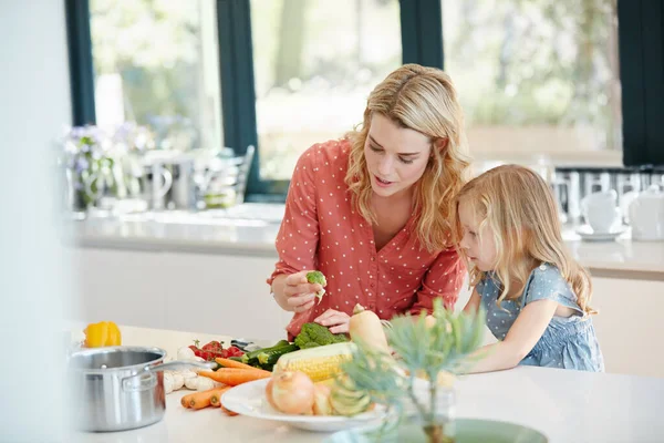 Enseigner à sa petite fille tout sur les aliments nutritifs. Plan recadré d'une mère et sa fille préparant un repas ensemble à la maison. — Photo