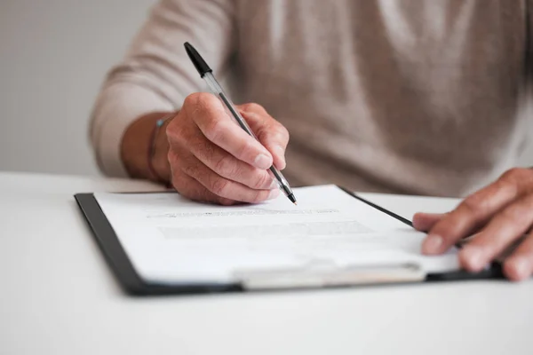 Op de stippellijn. Gesneden foto van een onherkenbare zakenman die een formulier invult op een klembord terwijl hij aan zijn bureau in het kantoor zit. — Stockfoto