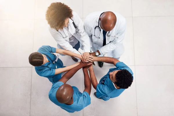 Empecemos este día. Inyección de ángulo alto de un grupo de médicos jóvenes que forman un grupo con las manos dentro de un hospital durante el día. —  Fotos de Stock