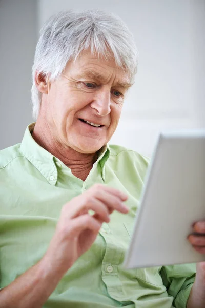 Conoscere la tecnologia. Girato di un uomo anziano che usa un tablet digitale seduto sul divano di casa. — Foto Stock