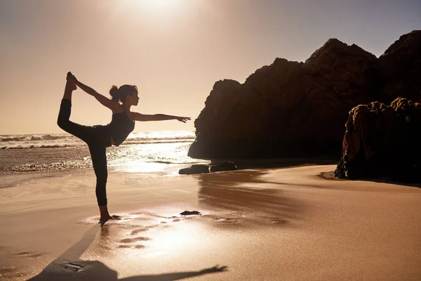 Yoga zal je leven ten goede veranderen. Foto van een jonge vrouw die yoga beoefent op het strand. — Stockfoto