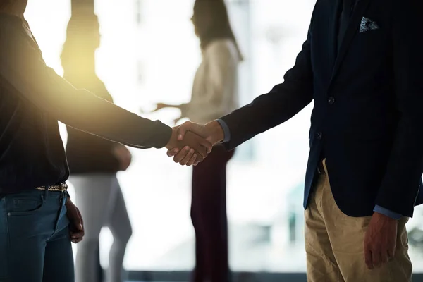 Its great to meet you. Shot of two silhouetted businesspeople shaking hands in front of a window in the office. — Stock Photo, Image