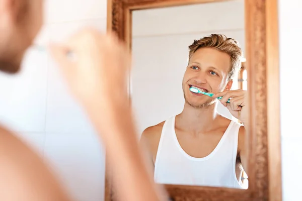 Minty fresh breath is the way to start the day. Shot of a young man brushing his teeth at home. — Foto de Stock