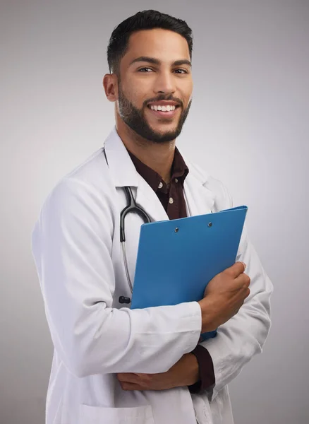 Ich sollte immer Arzt werden. Aufnahme eines hübschen jungen Arztes, der allein im Studio steht und ein Klemmbrett hält. — Stockfoto