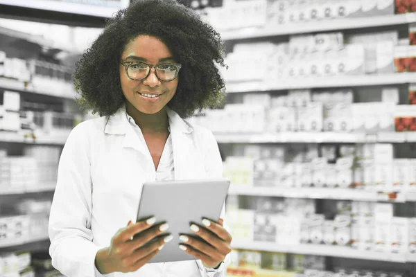 We make no mistakes. Portrait of a cheerful young female pharmacist standing with a digital tablet while looking at the camera in a pharmacy. — Stock Photo, Image