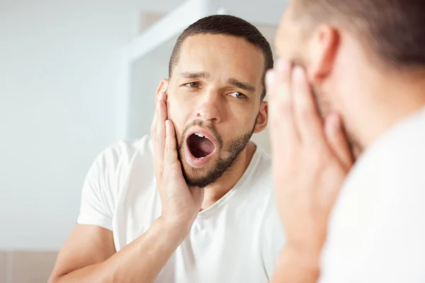 Waking up super early today was so helpful. Shot of a young man yawning while looking at his reflection in the bathroom mirror. — Stock Photo, Image
