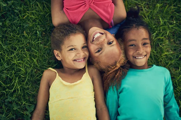 Frisk luft och roligt. Hög vinkel porträtt av tre små flickor som ligger på gräset tillsammans utanför. — Stockfoto