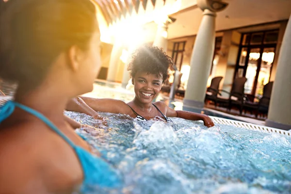 Happiness is treating yourself every now and then. Shot of two young women relaxing in a jacuzzi. — Photo