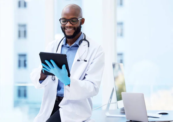 Controleren van de laatste testresultaten voor het nieuwe geneesmiddel. Schot van een knappe jonge arts die alleen in zijn kliniek zit en een digitale tablet gebruikt. — Stockfoto