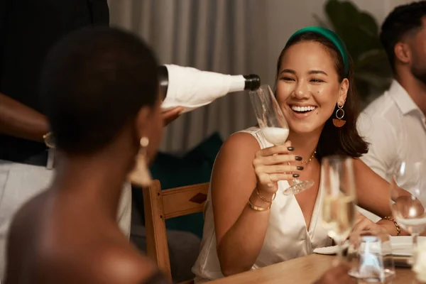 I cant pass up on more champagne. Shot of an unrecognizable man standing and pouring champagne into a glass for a friend during a dinner party. — Photo