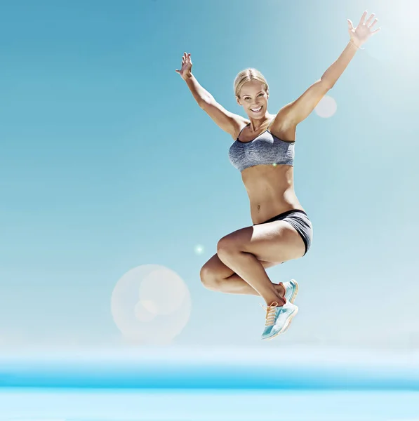 Full of energy and enthusiasm. Shot of a young woman in workout gear jumping in the air. — Foto de Stock