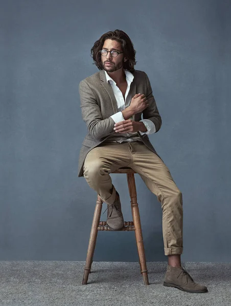 Lui ha stile. Scatto completo in studio di un giovane uomo bello ed elegante seduto su uno sgabello su uno sfondo grigio. — Foto Stock