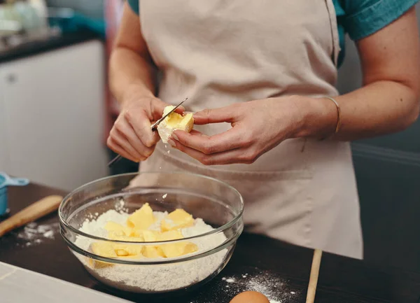 Hornear no es solo un hobby, es una pasión. Foto recortada de una mujer irreconocible cortando bloques de mantequilla mientras hornea dentro de su cocina en casa. — Foto de Stock