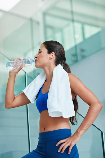 Bleibt hydratisiert, bleibt gesund. Aufnahme einer fitten jungen Frau, die beim Training Wasser trinkt. — Stockfoto