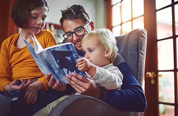 Απολαμβάνουν την ιστορία σαν οικογένεια. Φωτογραφία του πατέρα να διαβάζει ένα βιβλίο με το γιο και την κόρη του στο σπίτι.. — Φωτογραφία Αρχείου