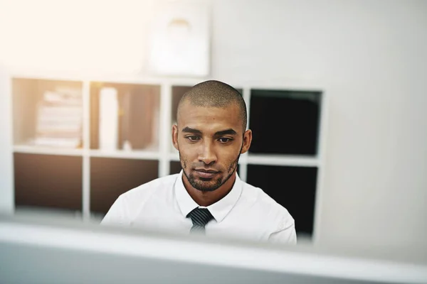 Sabe hasta dónde le llevará el trabajo duro. Fotografía de un joven hombre de negocios usando una computadora en el trabajo. —  Fotos de Stock