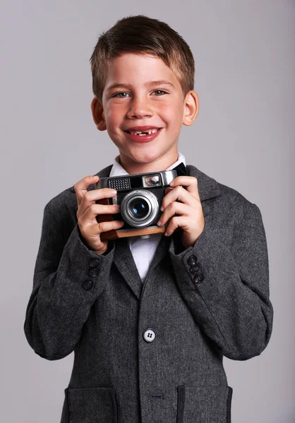 Jovem Weegee. Estúdio tiro de um menino em um terno velho segurando uma câmera vintage. — Fotografia de Stock