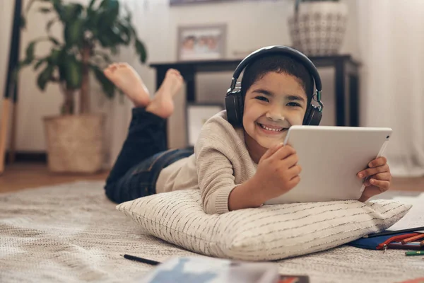 Nie można dostać się do biblioteki Wejdź audiobook. Strzał uroczego chłopca przy użyciu tabletu cyfrowego i słuchawek podczas wykonywania zadania szkolnego w domu. — Zdjęcie stockowe