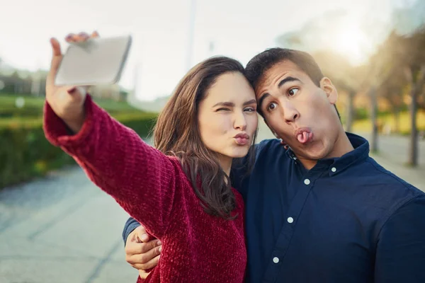 I found my soulmate in silliness. Shot of a young couple making funny faces while taking a selfie outdoors. —  Fotos de Stock