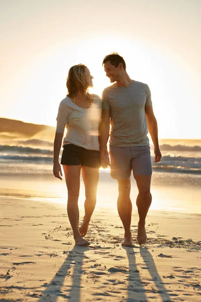 Sono così felice che posso appoggiarmi a lui. Girato di una coppia che cammina a stretto contatto sulla spiaggia al tramonto. — Foto Stock