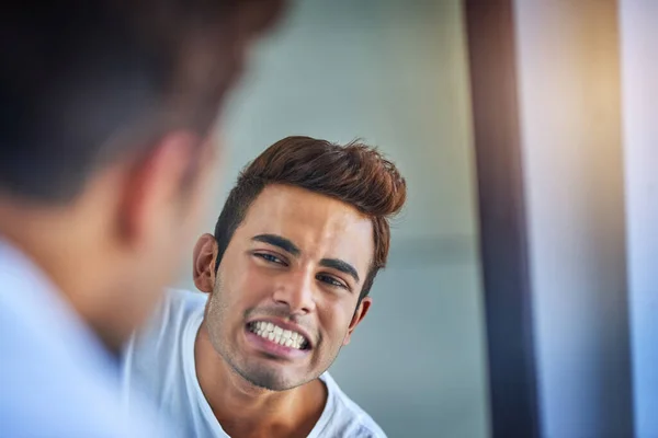 Zuby v bezvadném stavu. Postřelen pohledný mladý muž obdivující své čerstvě vyčištěné zuby v koupelnovém zrcadle. — Stock fotografie