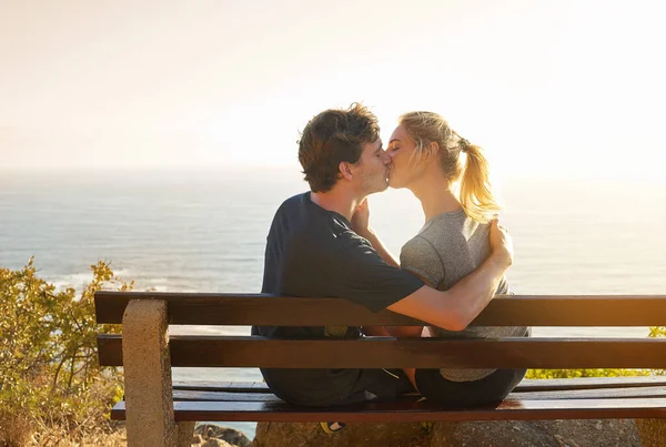 Quel bacio è sempre più bello del panorama. Girato di una coppia amorevole seduta su una panchina con vista sull'oceano. — Foto Stock