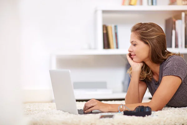 Whiling away the day online. Shot of a young woman using her laptop at home. — Stock Photo, Image