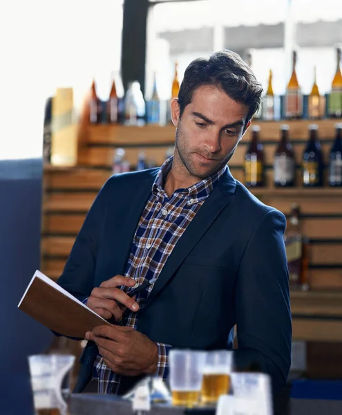 Berechnung des Verbrauchs. Aufnahme eines gutaussehenden jungen Mannes bei einer Bestandsaufnahme in einer Bar. — Stockfoto