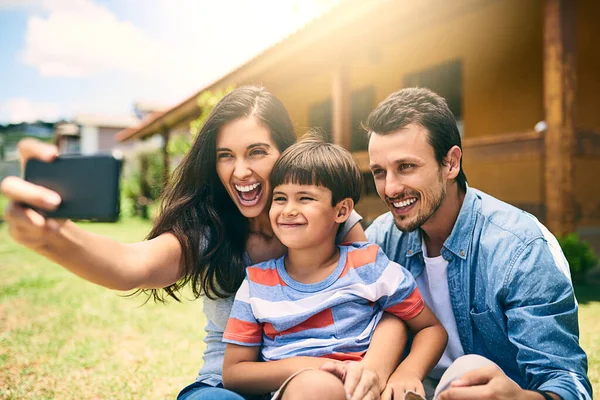 Це для фотоальбому. Обрізаний знімок щасливої молодої сім'ї з трьох взявши селфі білий сидить на задньому дворі . — стокове фото