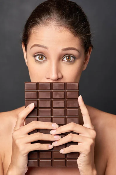 Ela é uma amante do chocolate. Estúdio tiro de uma jovem atraente sendo tentada por algo doce. — Fotografia de Stock