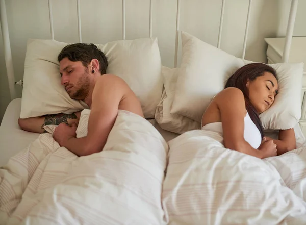 Never go to bed angry. Shot of a young couple sleeping on opposite sides of the bed at home. — ストック写真