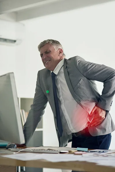 Experiencing an unexpected cramp. Shot of a businesswoman grimacing while holding a sore spot on his back in the office. — Stock Photo, Image