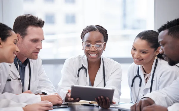 Titta på det här. Beskuren bild av en grupp unga läkare som tittar på en tablett under ett möte i sjukhusets styrelserum. — Stockfoto