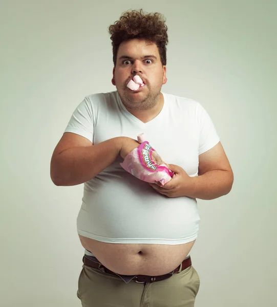 Debe tener más malvaviscos. Un disparo de un hombre con sobrepeso con malvaviscos metidos en la boca. — Foto de Stock