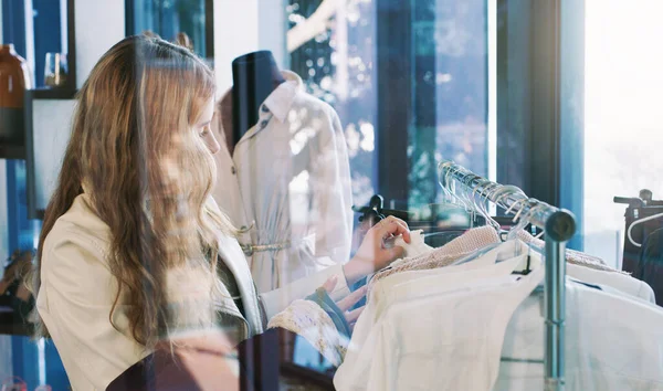 Shop til you drop. Shot of a young woman browsing through clothes in a boutique. — Foto de Stock