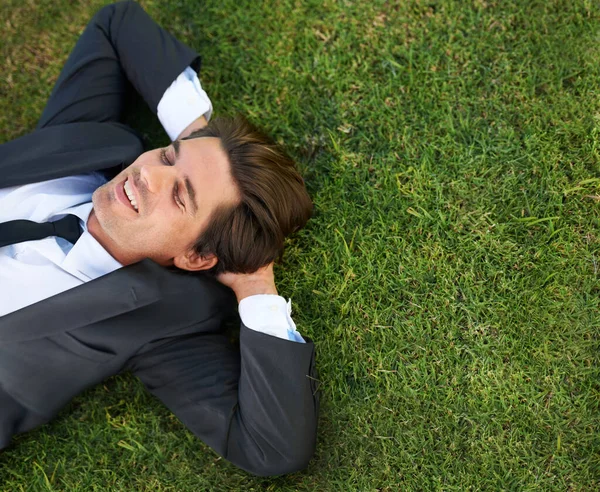 只是休息一下。一个年轻的商人躺在绿草上. — 图库照片