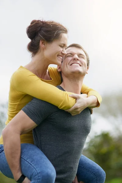 Liefde maakt tijd voor plezier. Schot van een gelukkige man die zijn vrouw een lift buiten geeft.. — Stockfoto