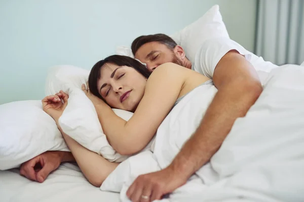 Zu bequem, um aus dem Bett zu kommen. Aufnahme eines entspannten jungen Paares, das sich in den Morgenstunden im Bett in den Armen liegt. — Stockfoto